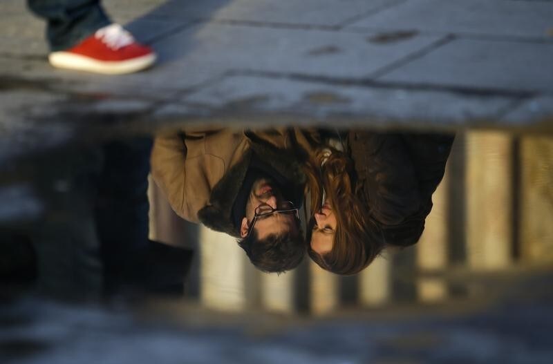 A couple is reflected in a puddle as they embrace on Valentine's Day in Venice February 14, 2014. REUTERS/Max Rossi (ITALY - Tags: SOCIETY) - GM1EA2F059S01