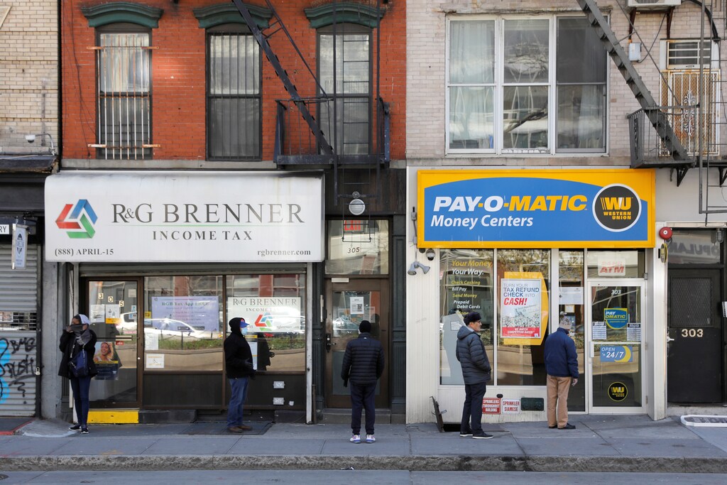 People queue to enter Payomatic, a business that offers check cashing, as unemployment claim figures were released, during the coronavirus disease (COVID-19) outbreak in Manhattan, New York City, New York, U.S., April 2, 2020. REUTERS/Andrew Kelly - RC2IWF9MM1UY