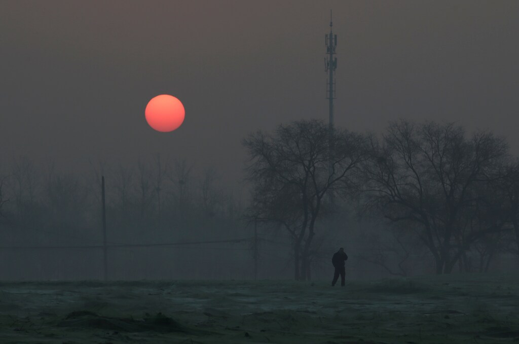 A man walks during sunrise in smog on a polluted day as a red alert issued for air pollution in Beijing, China, December 19, 2016. REUTERS/Jason Lee - RC19182B6B70