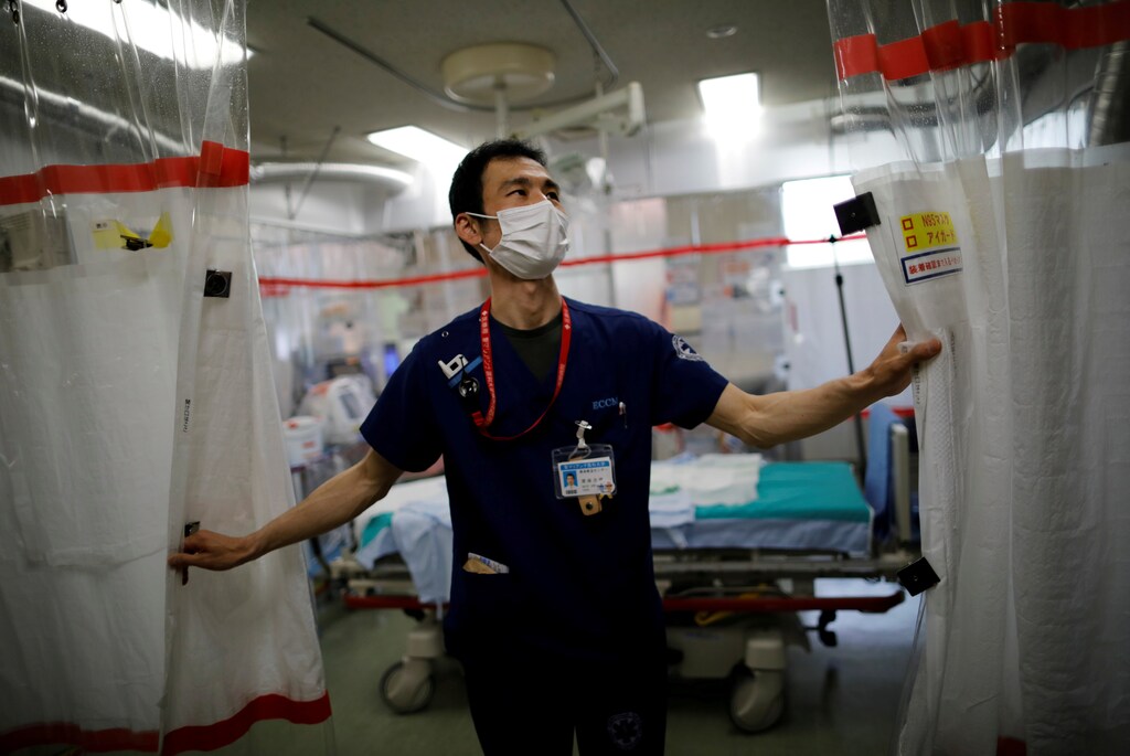 St. Marianna University Yokohama Seibu Hospital department of emergency and critical care medicine doctor Hiroki Saito draws plastic curtain at emergency and critical care room inside the hospital where patients suffering from the coronavirus disease (COVID-19) are being treated in Yokohama, south of Tokyo, Japan May 25, 2021. Picture taken May 25, 2021. REUTERS/Issei Kato/File Photo