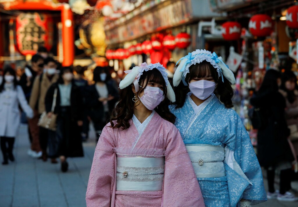 Visitors wearing protective face masks walk under decorations for the New Year at Nakamise street leading to Senso-ji temple at Asakusa district, a popular sightseeing spot in Tokyo, Japan.