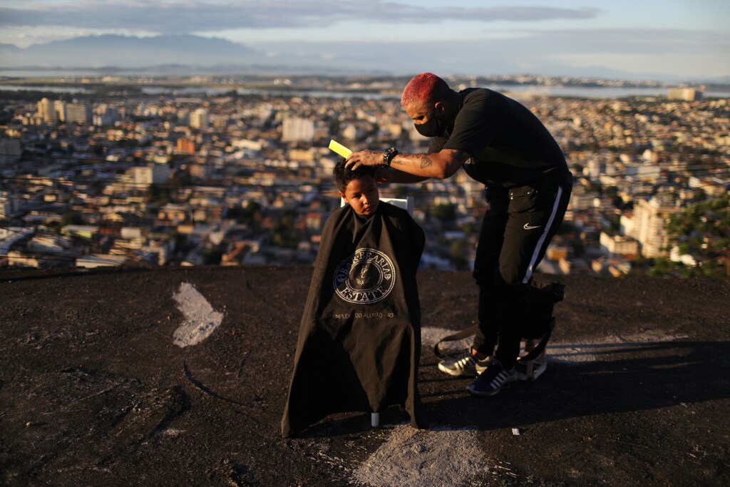 Barber Renan Estate gives a haircut to a child at home as part of his "Delivery Barber" service, as his shop is closed due to the coronavirus disease (COVID-19) outbreak, in the Complexo do Alemao slum in Rio de Janeiro, Brazil June 22, 2020. REUTERS/Pilar Olivares - RC2NEH9EJ26N