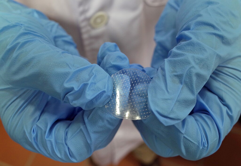 National University of Singapore's Kang Lifeng shows a sample of a microneedle patch that his team of researchers have pioneered at the university in Singapore September 11, 2014. The microneedle patch, made up of dozens of needles 600 microns long (0.6 millimetre) and half as wide, can deliver encapsulated dosages of drugs into the bloodstream through the skin painlessly, as compared to injections. According to Kang, the innovation, which is awaiting clinical trial, can be used potentially for cosmetic and skincare purposes to deliver collagen to inner skin layers, as well as non-invasive administration of drugs such as painkillers and insulin for patients in homecare settings. REUTERS/Edgar Su (SINGAPORE - Tags: HEALTH DRUGS SOCIETY) - GM1EA9B10L301