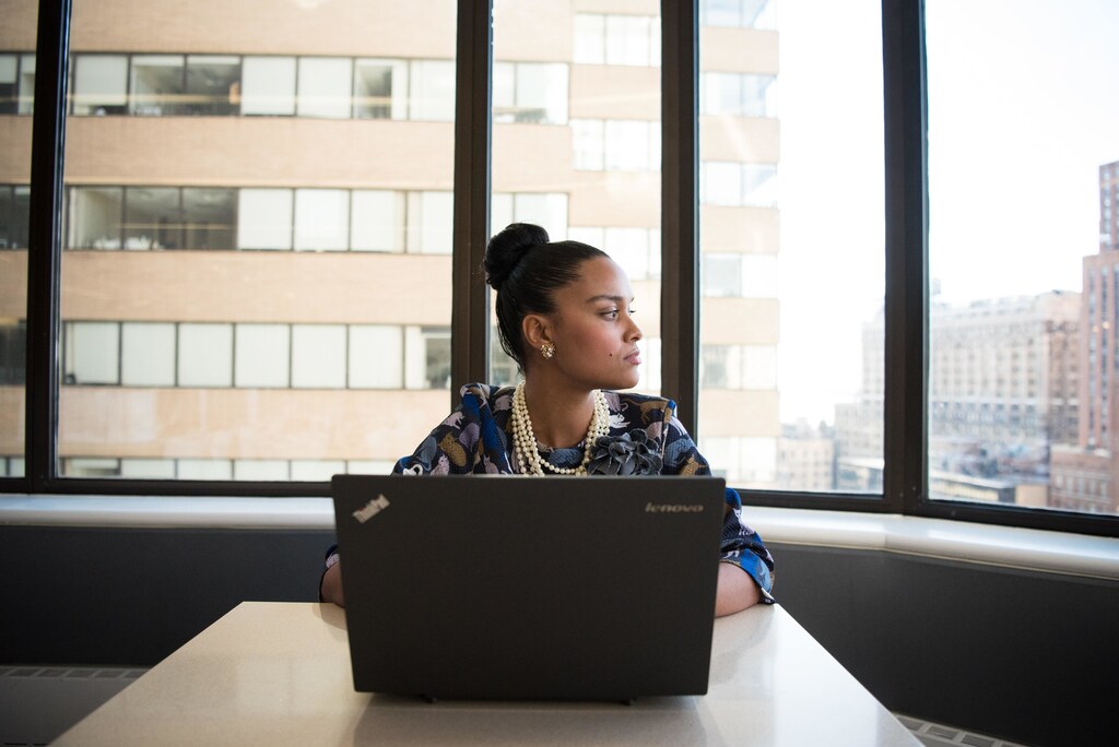 Woman sat at table in front of a black laptop.