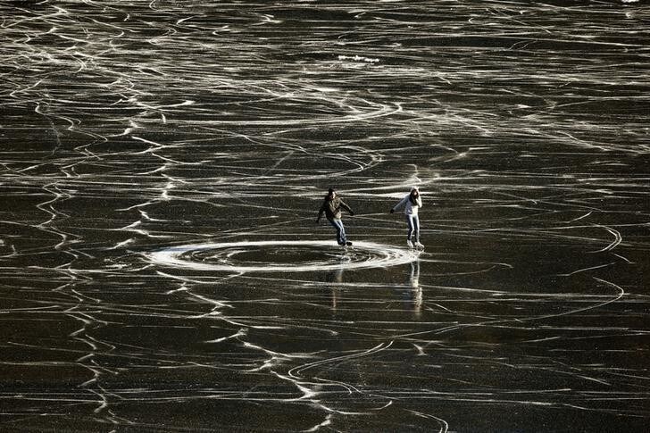 A couple skates on the frozen waters of Lake St. Moritz during a sunny winter day in the Swiss mountain resort of St. Moritz December 14, 2013. REUTERS/Arnd Wiegmann (SWITZERLAND - Tags: SOCIETY ENVIRONMENT TPX IMAGES OF THE DAY)