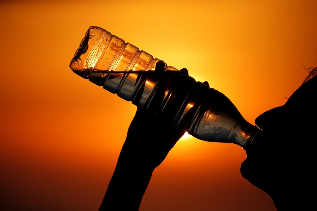 A woman drinks water during sunset as a heatwave hits France, in Cagnicourt near Cambrai, France, June 25, 2019. REUTERS/Pascal Rossignol - RC14613C4860