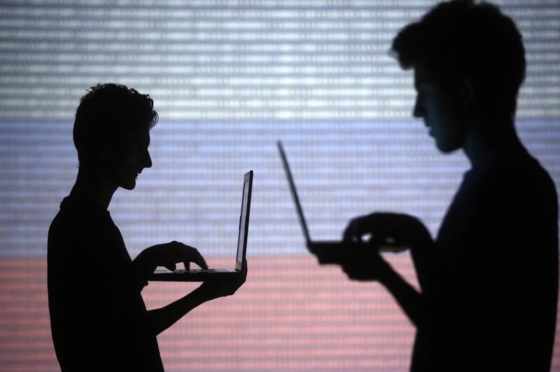 People are silhouetted as they pose with laptops in front of a screen projected with binary code and a Russian national flag, in this picture illustration taken in Zenica October 29, 2014. REUTERS/Dado Ruvic (BOSNIA AND HERZEGOVINA - Tags: SCIENCE TECHNOLOGY) - LR1EAAT0YAC6S