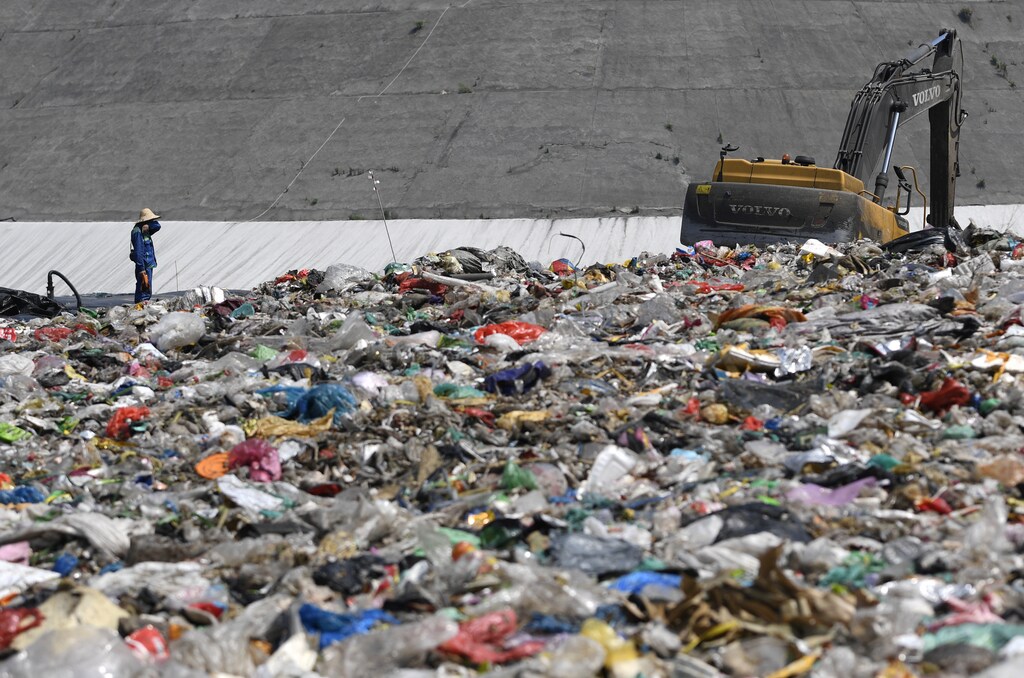 An environmental worker stands near an excavator amid waste at Tianziling landfill in Hangzhou, Zhejiang province, China August 7, 2019. Picture taken August 7, 2019. REUTERS/Stringer ATTENTION EDITORS - THIS IMAGE WAS PROVIDED BY A THIRD PARTY. CHINA OUT. - RC16566D9530