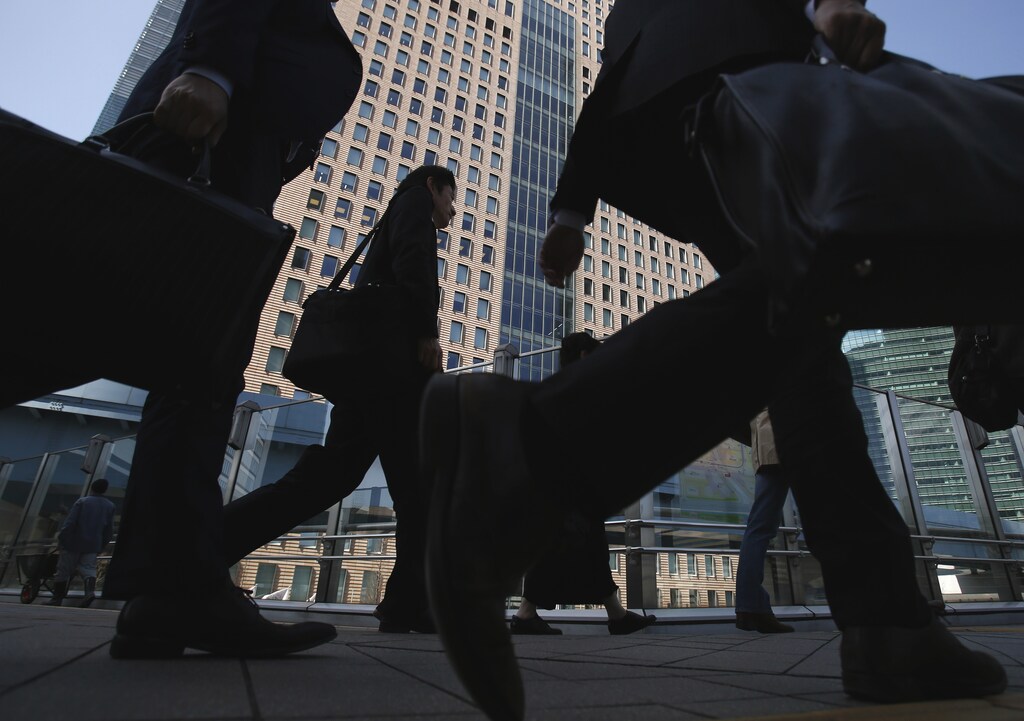 People walk on an overpass in a business district of Tokyo, March 17, 2015.