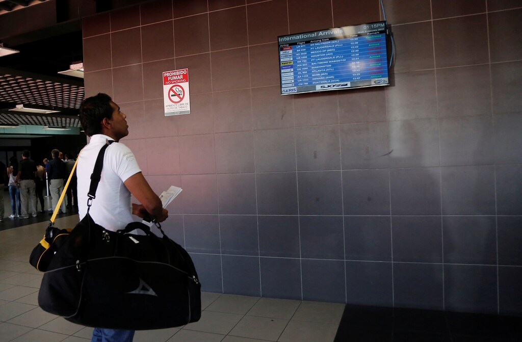 A stranded passenger checks a flight information board at Juan Santamaria airport, following the closure of airport operations due to an eruption of Turrialba volcano in Alajuela, Costa Rica January 4, 2017. REUTERS/Juan Carlos Ulate - RTX2XKNZ