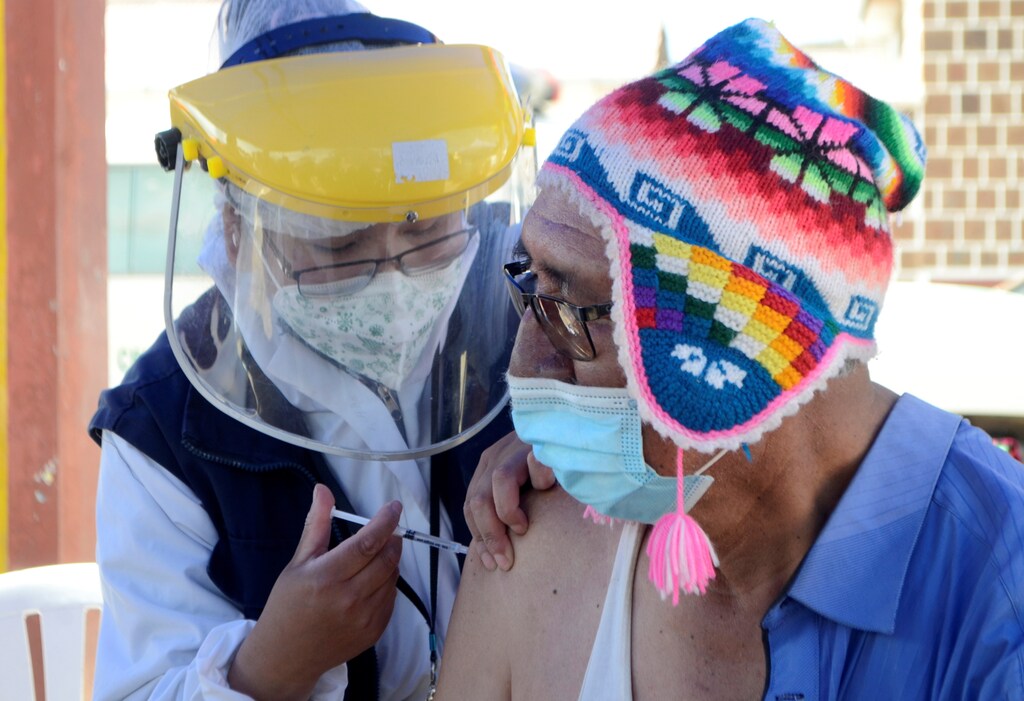 A man in a South-American style hat receives a COVID vaccine.