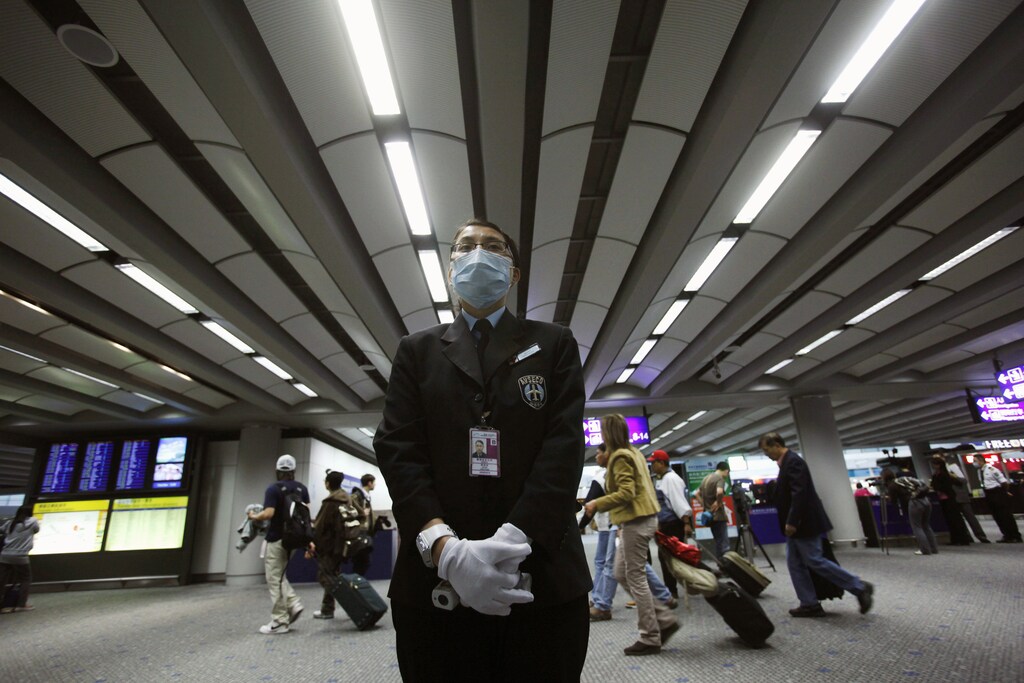 A health worker stands by ready to ask incoming passengers to remove any head gears before temperature screenings at the International Airport in Hong Kong April 27, 2009. Asia, a continent that has battled deadly viruses such as the H5N1 bird flu and SARS in recent years, began taking steps over the weekend to ward off a new flu virus. REUTERS/Vincent Yu/Pool (CHINA POLITICS HEALTH IMAGES OF THE DAY) - GM1E54R15DW01