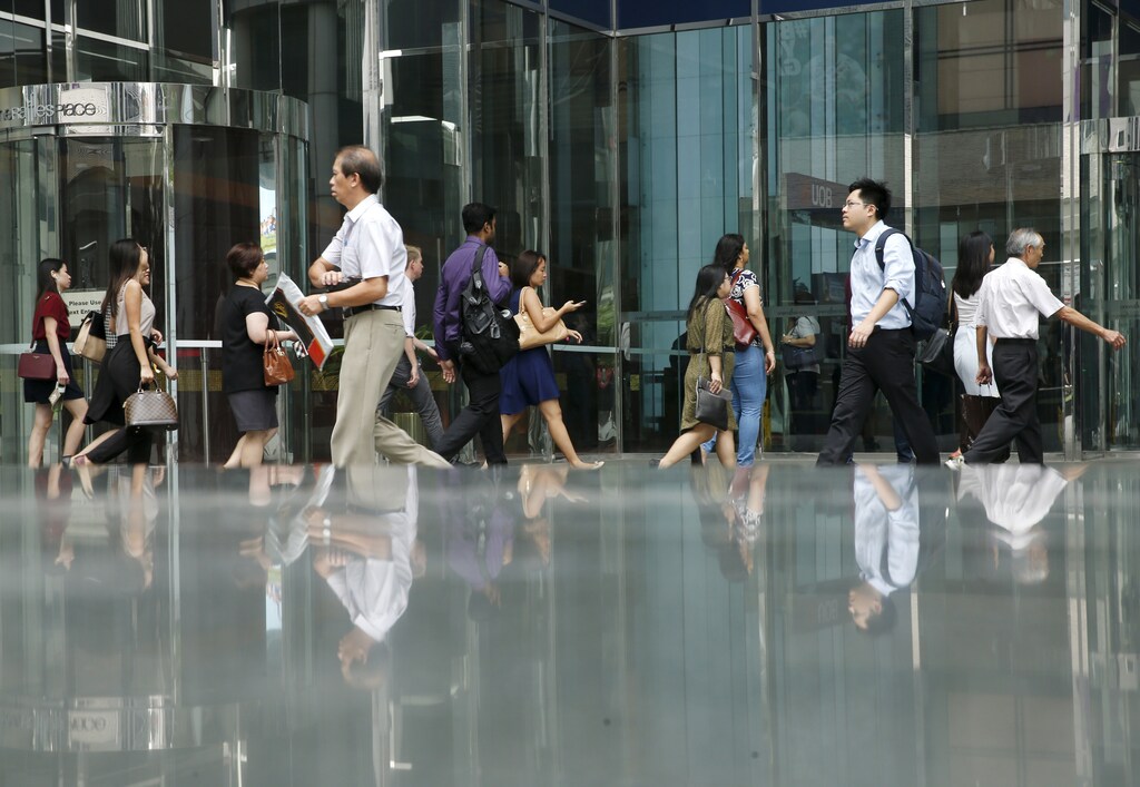 Office workers walk to work during morning peak hour commute in the central business district in Singapore March 24, 2016