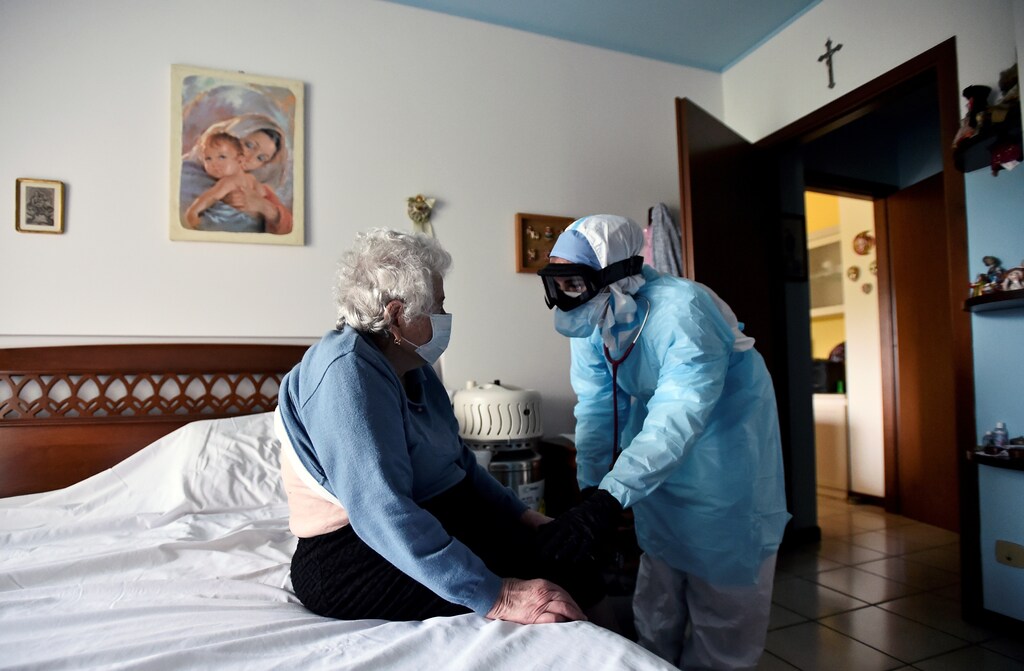 A doctor in protective suit visits a person suffering from the coronavirus disease (COVID-19) at her home in Bergamo, the epicentre of Italy's outbreak, April 16, 2020. Patients with symptoms that are not too severe are treated at home in Bergamo, to avoid overcrowding hospitals already overwhelmed with patients needing intensive care. REUTERS/Flavio Lo Scalzo TPX IMAGES OF THE DAY - RC2T5G9PUGEC