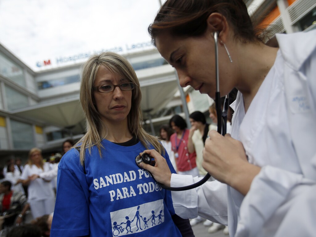 A health worker pretends to be a doctor using a stethoscope on a patient during a protest against the local government's plans to cut public healthcare spending outside Infanta Leonor hospital in Madrid May 7, 2013. The T-shirt reads, "Public health for all". REUTERS/Sergio Perez (SPAIN - Tags: HEALTH POLITICS BUSINESS CIVIL UNREST) - RTXZDH7