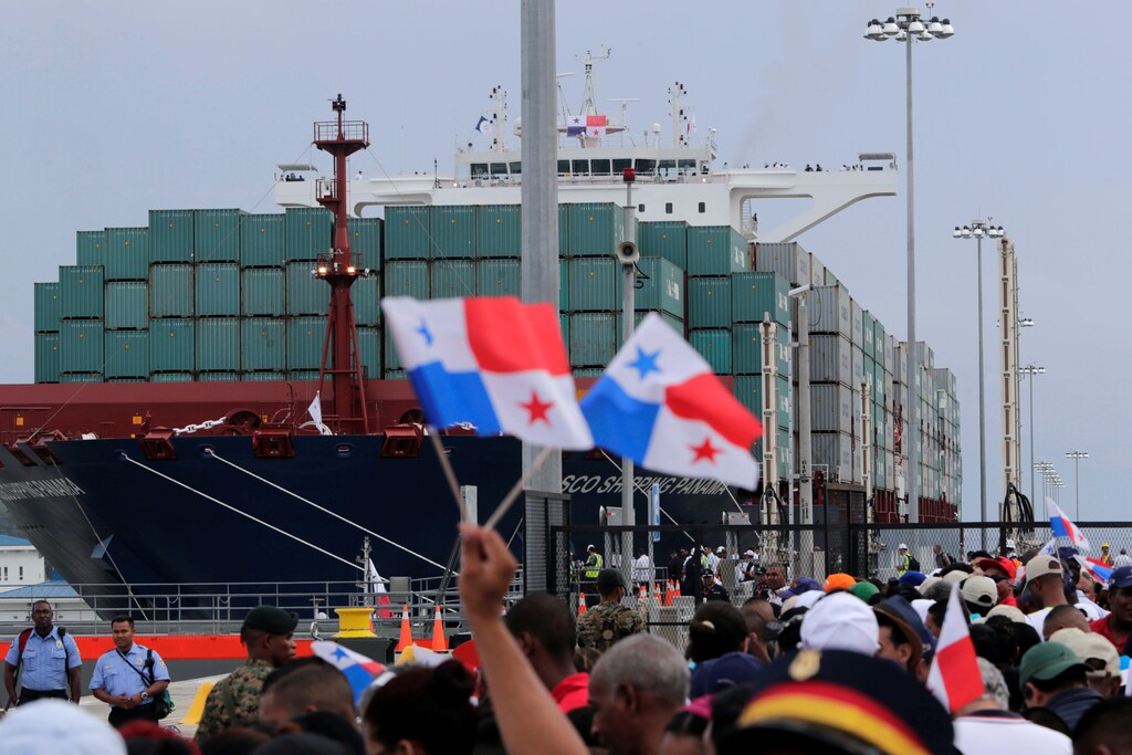 People wave Panama flags as they wait for the Chinese COSCO container vessel named Andronikos to navigate through the Agua Clara locks during the first ceremonial pass through the newly expanded Panama Canal in Agua Clara, on the outskirts of Colon City, Panama June 26, 2016.