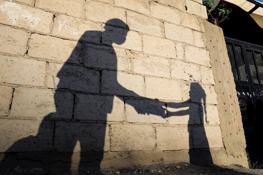 The shadow of a girl receiving a meal for iftar, or the evening meal, to break fast from a member of "Tkiyet Um Ali" humanitarian services center is cast on a wall in front of her family home in the city of Russeifa, during the holy fasting month of Ramadan, amid concerns over the spread of coronavirus disease (COVID-19), in Jordan, April 28, 2020. Picture taken April 28, 2020. REUTERS/Muhammad Hamed TPX IMAGES OF THE DAY - RC2ZDG987UP8