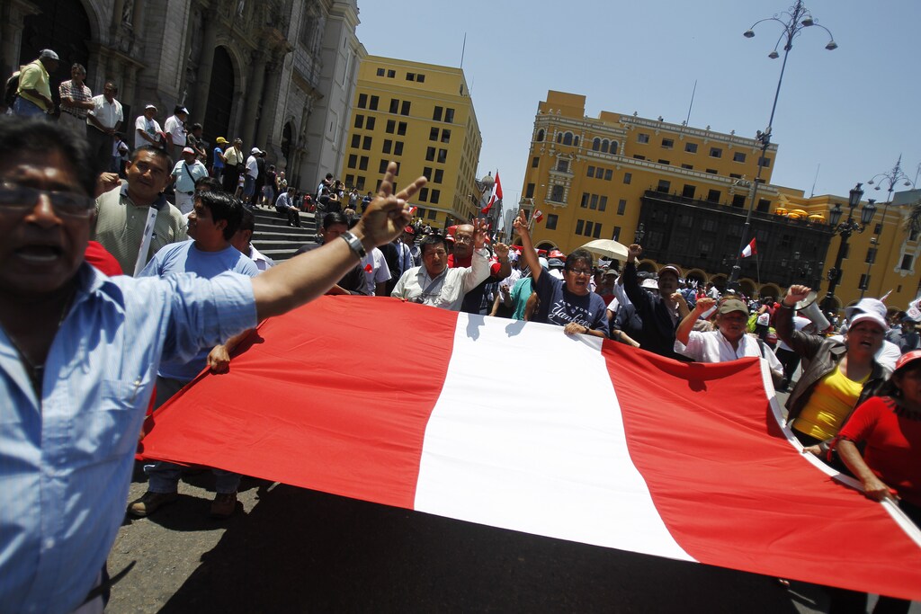 People demonstrate while holding a Peruvian flag during the final ruling court session of a decades-old maritime dispute between Peru and Chile, in front of the Government Palace in Lima January 27, 2014. Chile's claim over rich fishing grounds in the Pacific Ocean, disputed by Peru, was upheld by an international court on Monday, ending one of Latin America's last big border spats. The decision by the International Court of Justice relates to 38,000 square metres of ocean that are currently controlled by Chile. REUTERS/Enrique Castro-Mendivil (PERU - Tags: POLITICS MARITIME) - RTX17X8Q