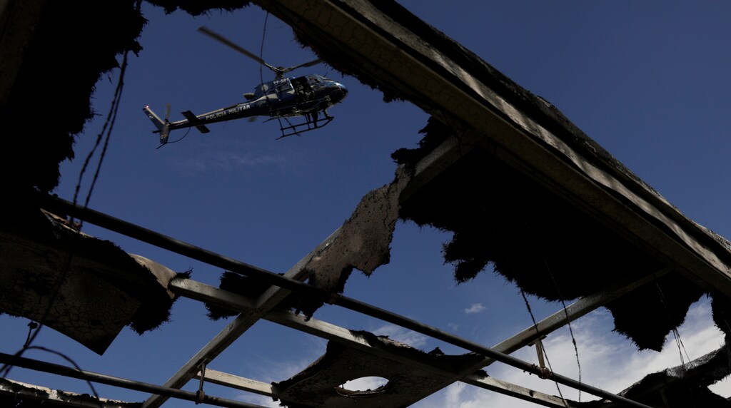 A police helicopter flies over a burned bus damaged during violent clashes between rival gangs at Brasil avenue near Cidade Alta slum in Rio de Janeiro, Brazil, May 2, 2017. REUTERS/Ricardo Moraes - RTS14TOI