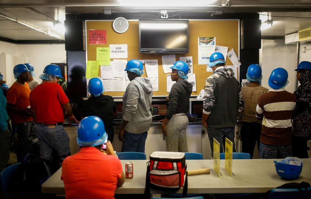 Temporary foreign workers stand in front of job posting board during their lunch break at the Highline Mushrooms farm, Canada's largest mushroom grower, in Leamington, Ontario, Canada, April 14, 2016.
