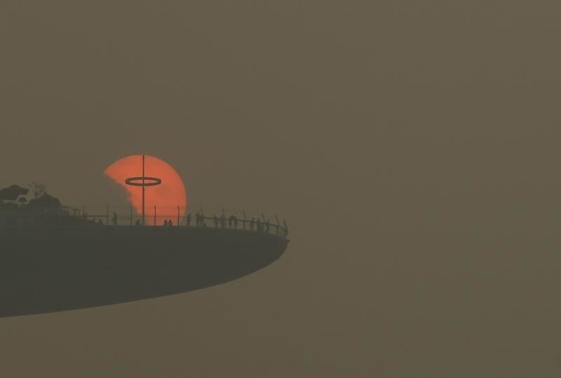 People watch the sun set from the observatory deck of the Marina Bay Sands hotel in Singapore October 5, 2015. The 3-hour haze Pollutant Standards Index (PSI) reached a high of 186 at 4pm on Monday, according to the National Environment Agency. Slash-and-burn agriculture in neighboring Indonesia has blanketed Singapore in a choking haze for weeks. REUTERS/Edgar Su TPX IMAGES OF THE DAY - GF10000232830