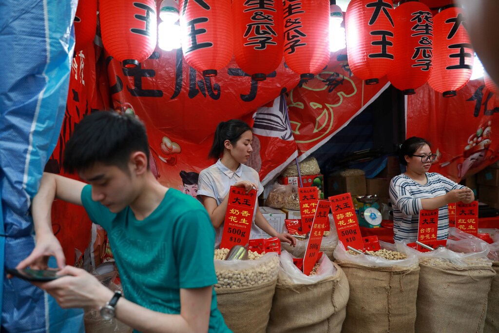 A man checks his mobile phone as vendors wait at their stand in Chinatown, Singapore January 27, 2018. Picture taken January 27, 2018. REUTERS/Soe Zeya Tun - RC12F435CD30