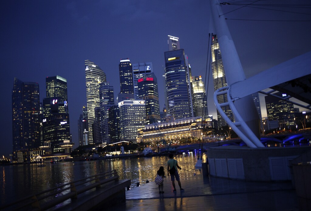 People take photos with the skyline of the financial district of Singapore in the background April 14, 2014. Singapore's central bank stuck to its tight monetary policy stance on Monday despite weaker growth in the first quarter, saying core inflation will remain elevated as a sustained recovery in advanced economies spurs a rebound in the city-state. REUTERS/Edgar Su (SINGAPORE - Tags: CITYSCAPE BUSINESS) - RTR3L7M7