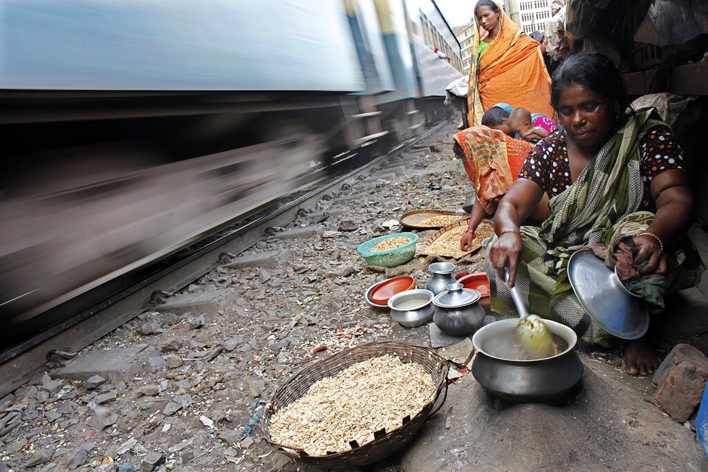 A woman cooks using a makeshift stove in a slum as a train passes by in Dhaka June 24, 2010. According to a recent survey jointly conducted by Bangladesh Bureau of Statistics and Unicef, the condition of city slum dwellers especially children and women is much worse than those in other parts of the country. REUTERS/Andrew Biraj (BANGLADESH - Tags: SOCIETY IMAGES OF THE DAY)