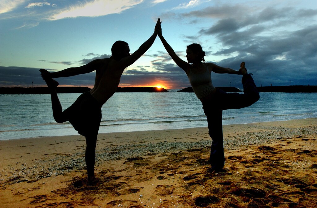 Darius Rustam, 30, and Tiffany Davis-Rustam (R) 27, from New York City, practice the King Dancer yoga pose during the sunset hours on Magic Island in Ala Moana Beach Park in Honolulu, Hawaii, January 21, 2004. The Rustams, both yoga instructors, are starting a tour of the Hawaiian Islands for five weeks. NO RIGHTS CLEARANCES OR PERMISSIONS ARE REQUIRED FOR THIS IMAGE REUTERS/Lucy Pemoni LP/HK - RP4DRIHKDIAA