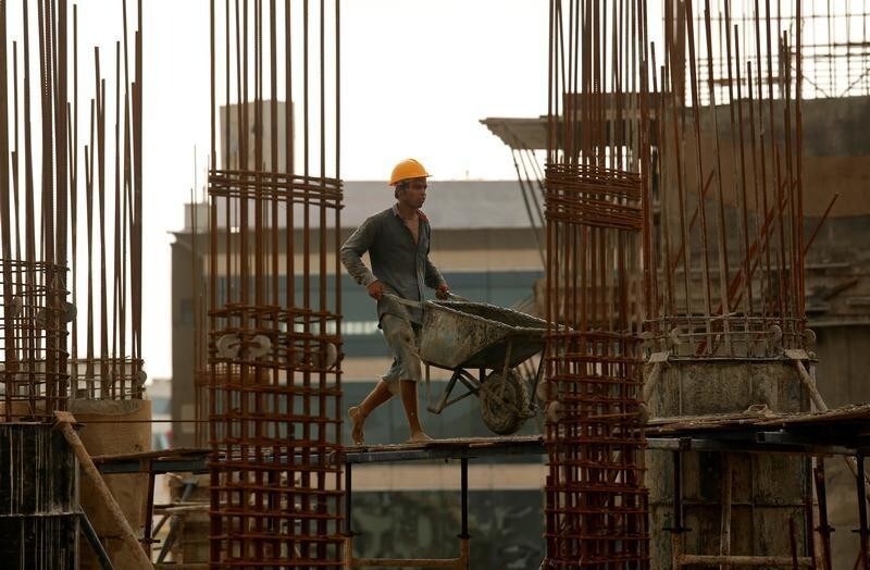 A worker pushes a wheelbarrow to collect cement at a construction site of a residential building in Mumbai, India, August 31, 2018.