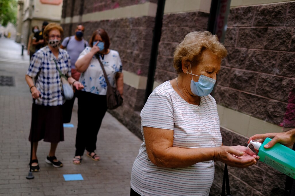 A volunteer applies alcohol hand gel to an elderly woman before she makes a PCR test in the Raval district, after Catalonia's regional authorities announced restrictions to contain the spread of the coronavirus disease (COVID-19) in Barcelona Spain September 17, 2020. REUTERS/Nacho Doce - RC2H0J99XU5G