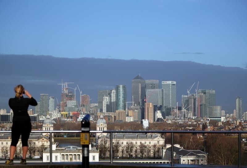 A woman takes a photograph of the Canary Wharf financial district from Greenwich Park in London, Britain, January 22, 2017. REUTERS/Hannah McKay - RC15C3830B40