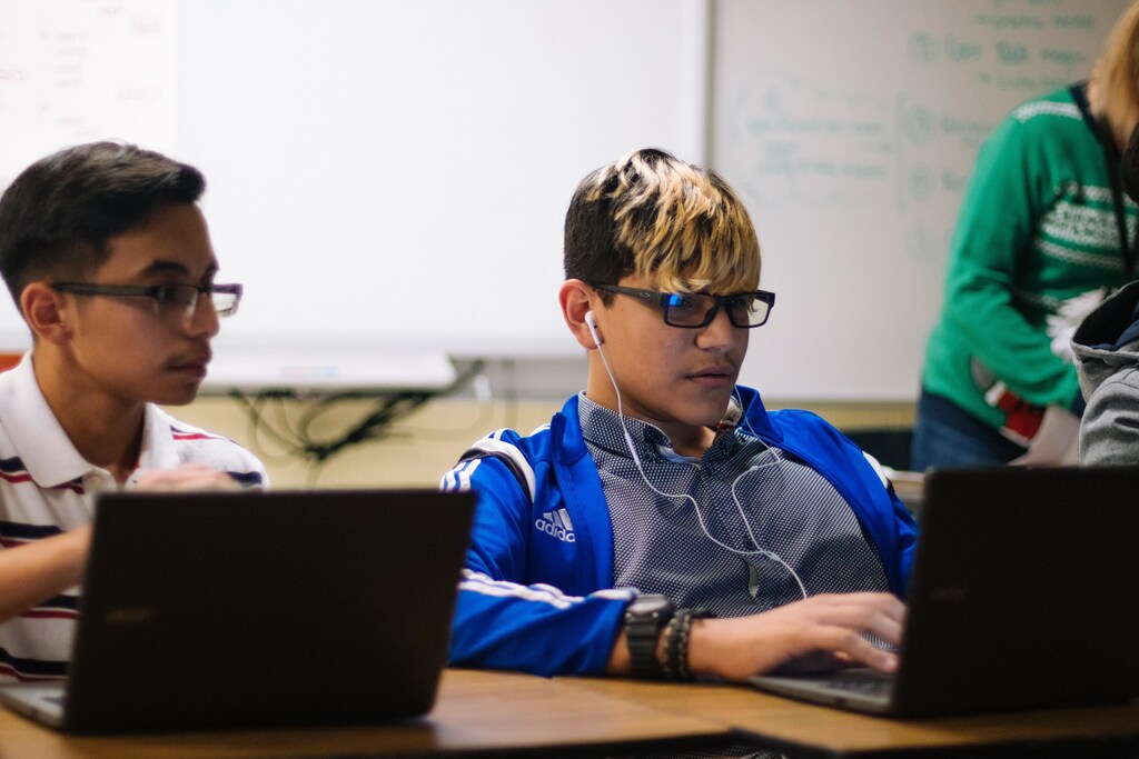 Teenagers in classroom working on laptops.
