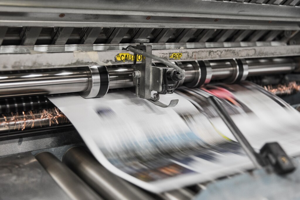 Newspapers rolling off the printing press, illustrating the dangers of deepfake news