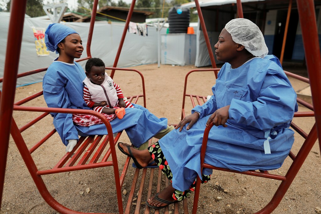 Noella Kavira Kitakya, 26, holding 16-month-old Kambale Eloge, whose mother died of Ebola, talks to Arlette Kavugho, 40, mother of six, in the courtyard of United Nations Children's Fund (UNICEF) creche for children whose families are suspected or confirmed Ebola cases, next to an Ebola treatment centre (ETC) in Katwa, near Butembo, in the Democratic Republic of Congo, October 2, 2019. Both women are Ebola survivors who now work as caregivers. Kavira survived Ebola last June with her two brothers but their mother and close family members succumbed to the virus. "I am often afraid to relapse but I was reassured that once victorious, there is no risk," she said. "I was treated effectively and it allowed me to heal. Others did not have the same luck," she added. "It is sad to see children becoming orphans because of Ebola." REUTERS/Zohra Bensemra SEARCH "EBOLA ZOHRA" FOR THIS STORY. SEARCH "WIDER IMAGE" FOR ALL STORIES. - RC12146CFD40