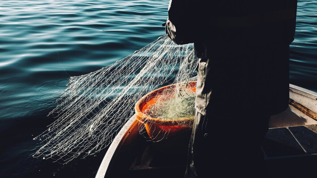 Primer plano de un pescador sosteniendo una red mientras pesca en el océano.