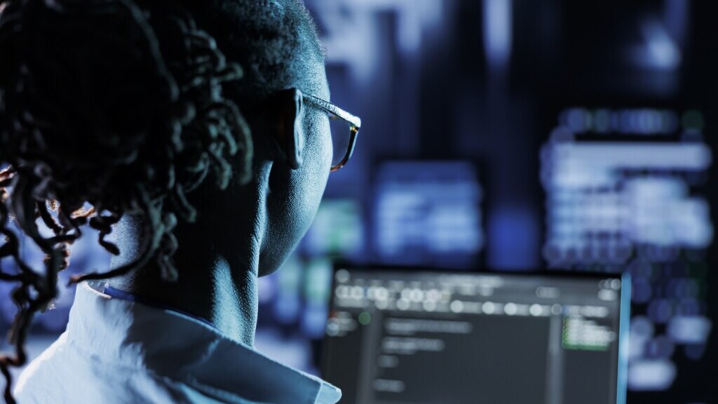 女性のサイバーセキュリティ専門家がコンピューター画面の前に座っている。