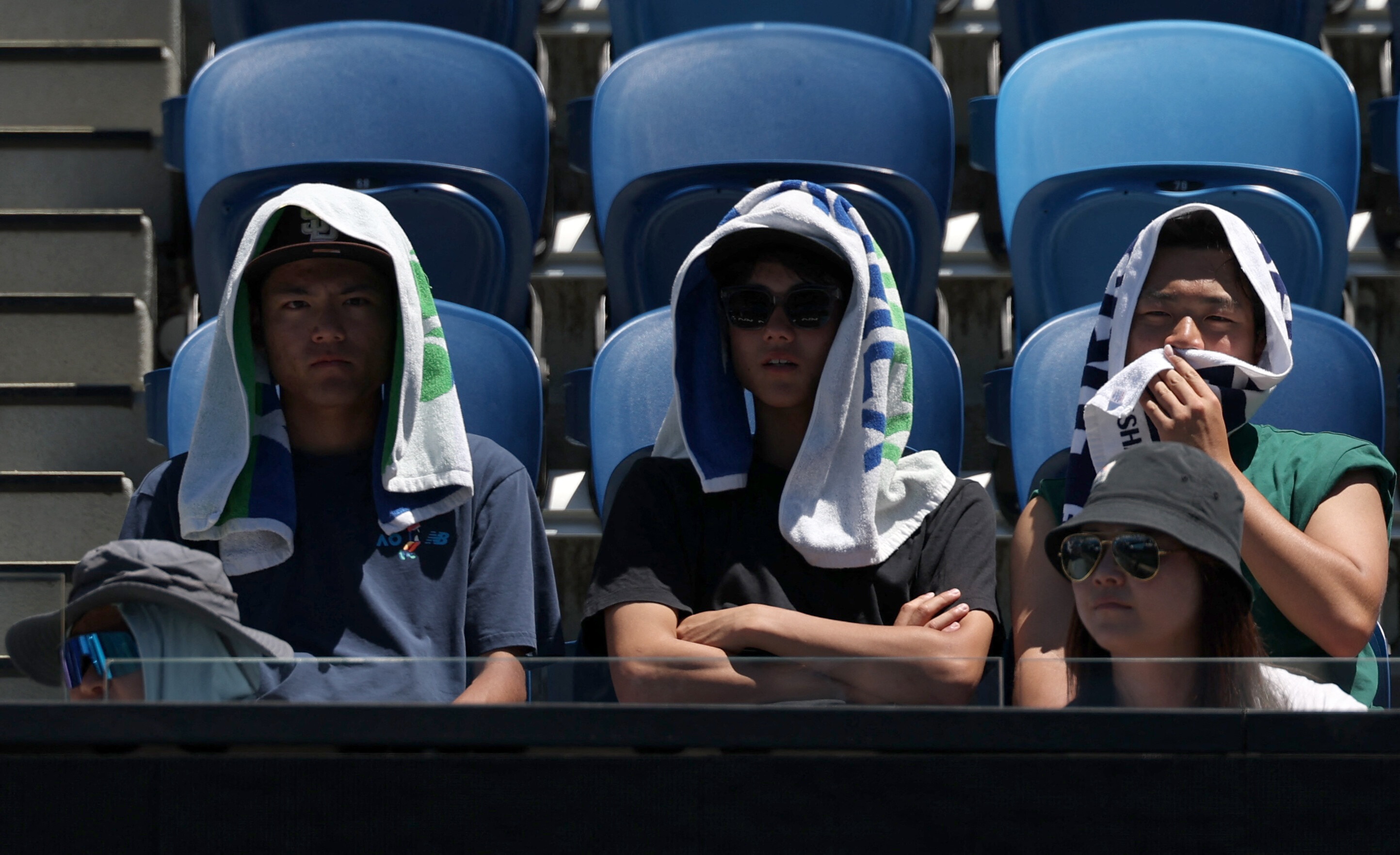 Tennis - Australian Open - Melbourne Park, Melbourne, Australia - January 24, 2026 Spectators in the stands use towels to cover from the heat during the third round match between Russia's Karen Khachanov and Italy's Luciano Darderi REUTERS/Hollie Adams