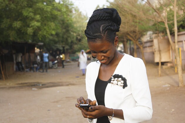 A smiling young woman writing a texto on her mobile phone.
