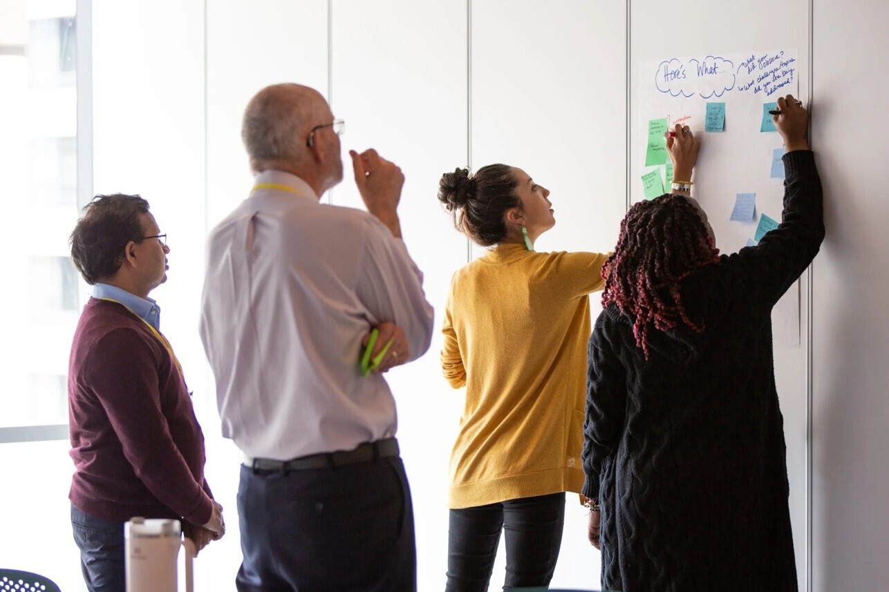 People are seen working together on a whiteboard.