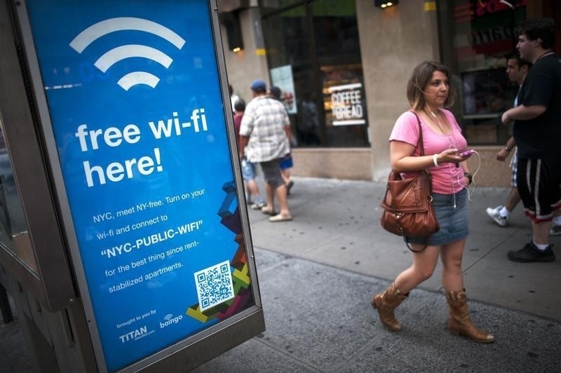 A woman walks past a WiFi-enabled phone booth in New York July 12, 2012. The New York City Department of Information Technology and Telecommunications have announced that they have converted 10 public pay phones into free WiFi hot spots as part of a pilot program to determine if it is possible to expand all city pay phones into a city-wide WiFi network.     