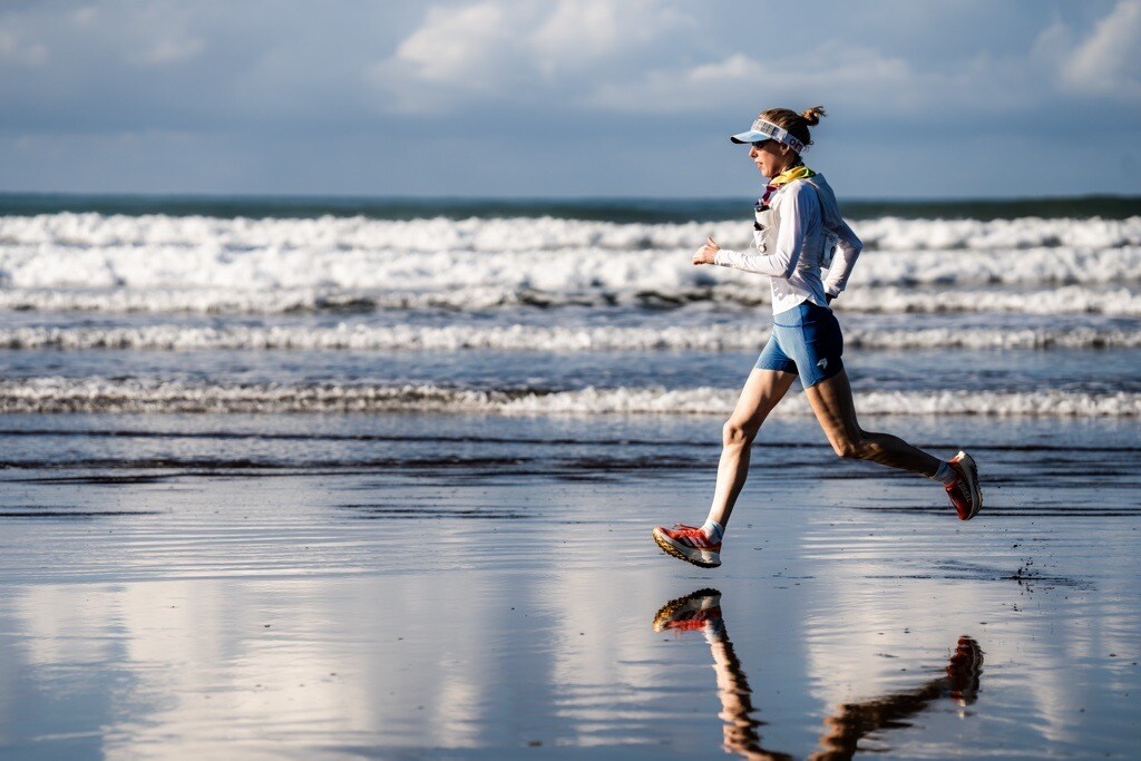A woman is see running along a beach.