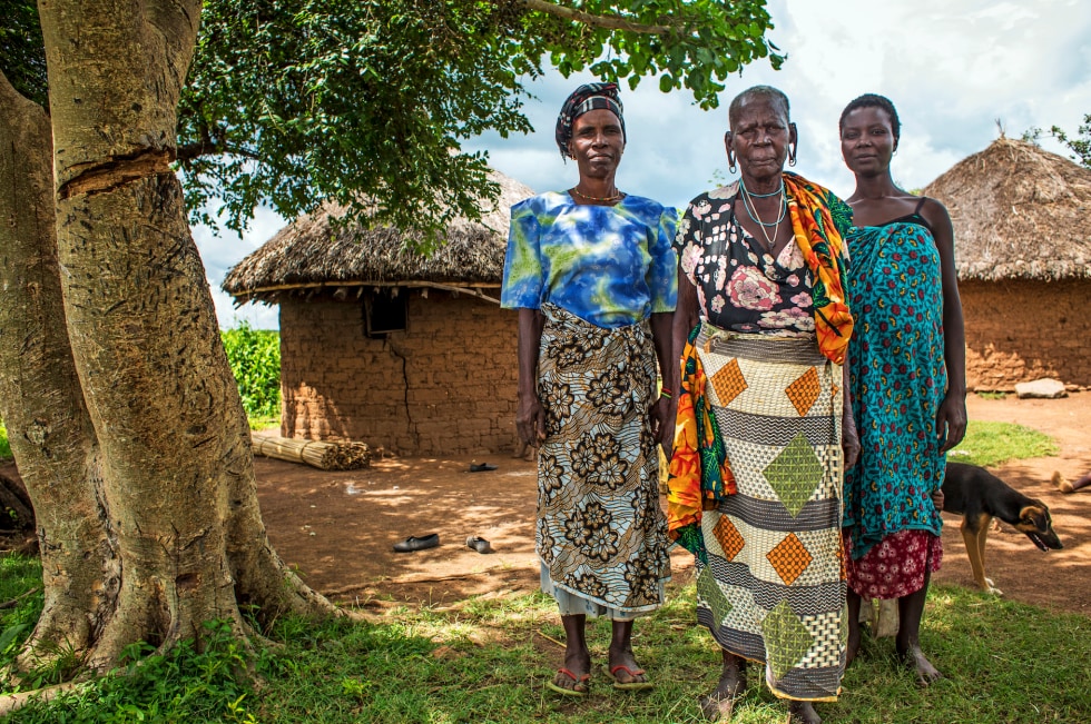  Mugosi Isombe, Veronica Nyagochera and Paulina Mukosa pose for a family portrait outside their home.   