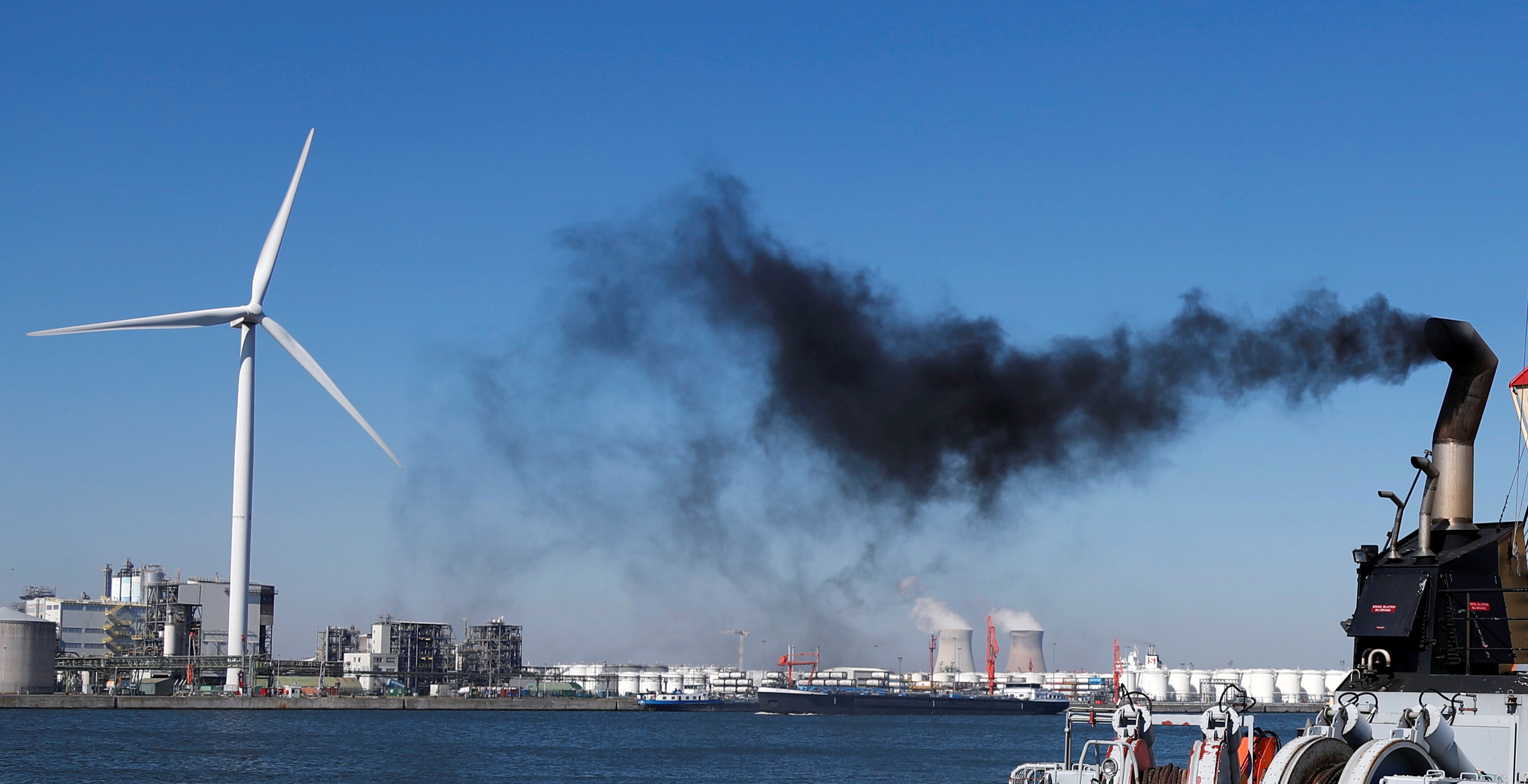 Smoke rises from a pilot boat near a wind turbine and the cooling towers of the Doel nuclear plant in the port of Antwerp during the coronavirus disease (COVID-19) outbreak, Belgium April 22, 2020