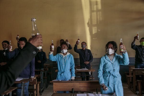 Des élèves brandissent des bouteilles de Covid Organics offertes par les autorités avant le début des cours au lycée J.-J. Rabearivelo, dans le centre d’Antananarivo, le 23 avril 2020.