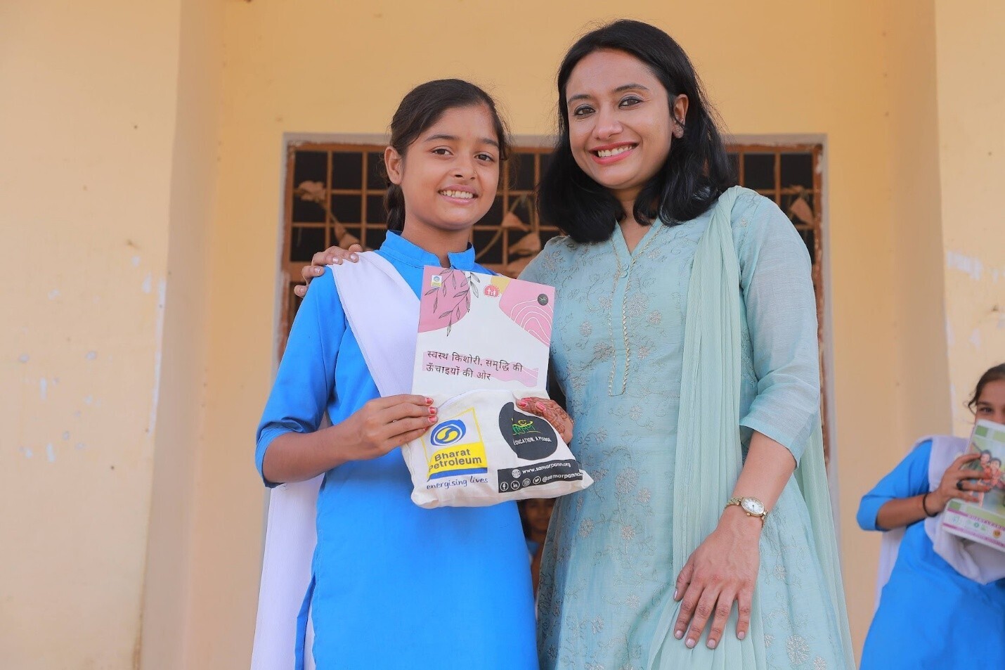 A school girl in a village in Madhya Pradesh, India, receives a pack of six reusable pads and an Info Booklet in Hindi by Samarpan.