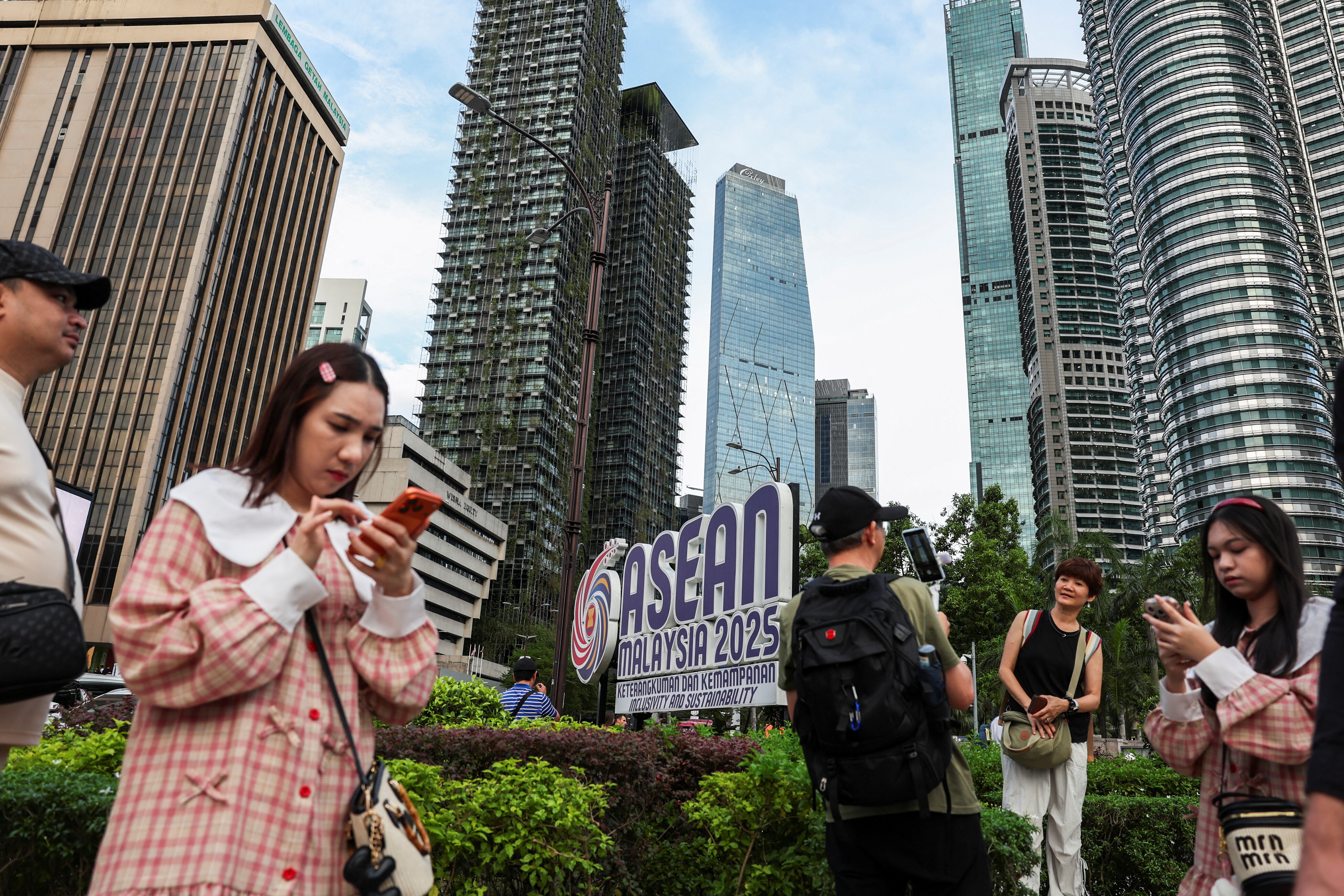 2025年10月24日、マレーシアのクアラルンプールにて、第47回ASEAN首脳会議を前に、ASEANのロゴマーク付近に集まる人々