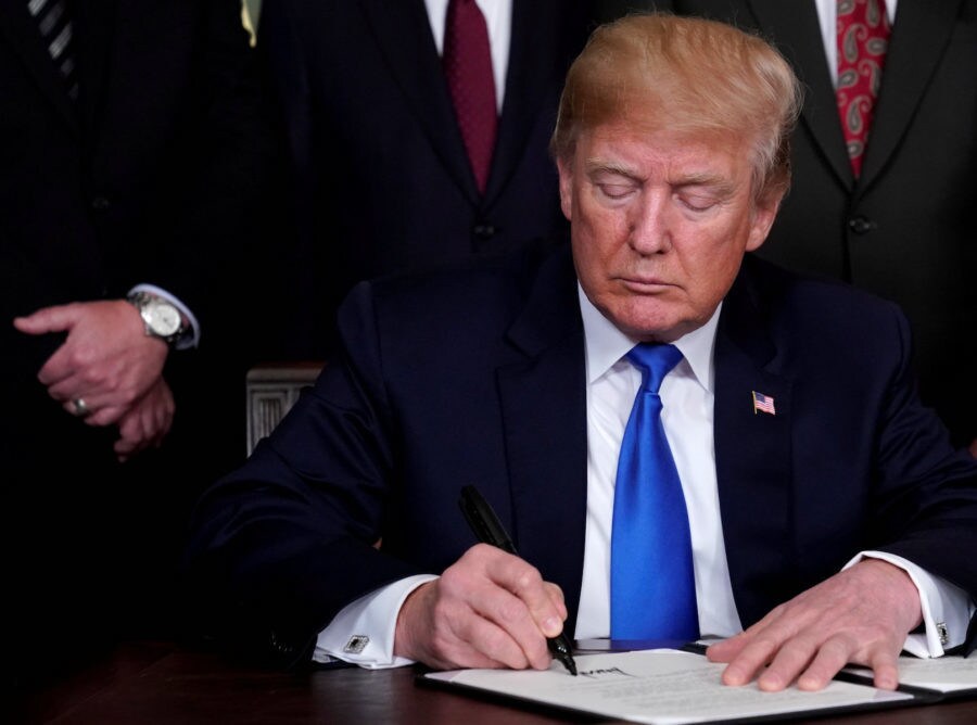 FILE PHOTO: U.S. President Donald Trump signs a memorandum on intellectual property tariffs on high-tech goods from China, at the White House in Washington, DC, U.S., March 22, 2018. REUTERS/Jonathan Ernst/File Photo
