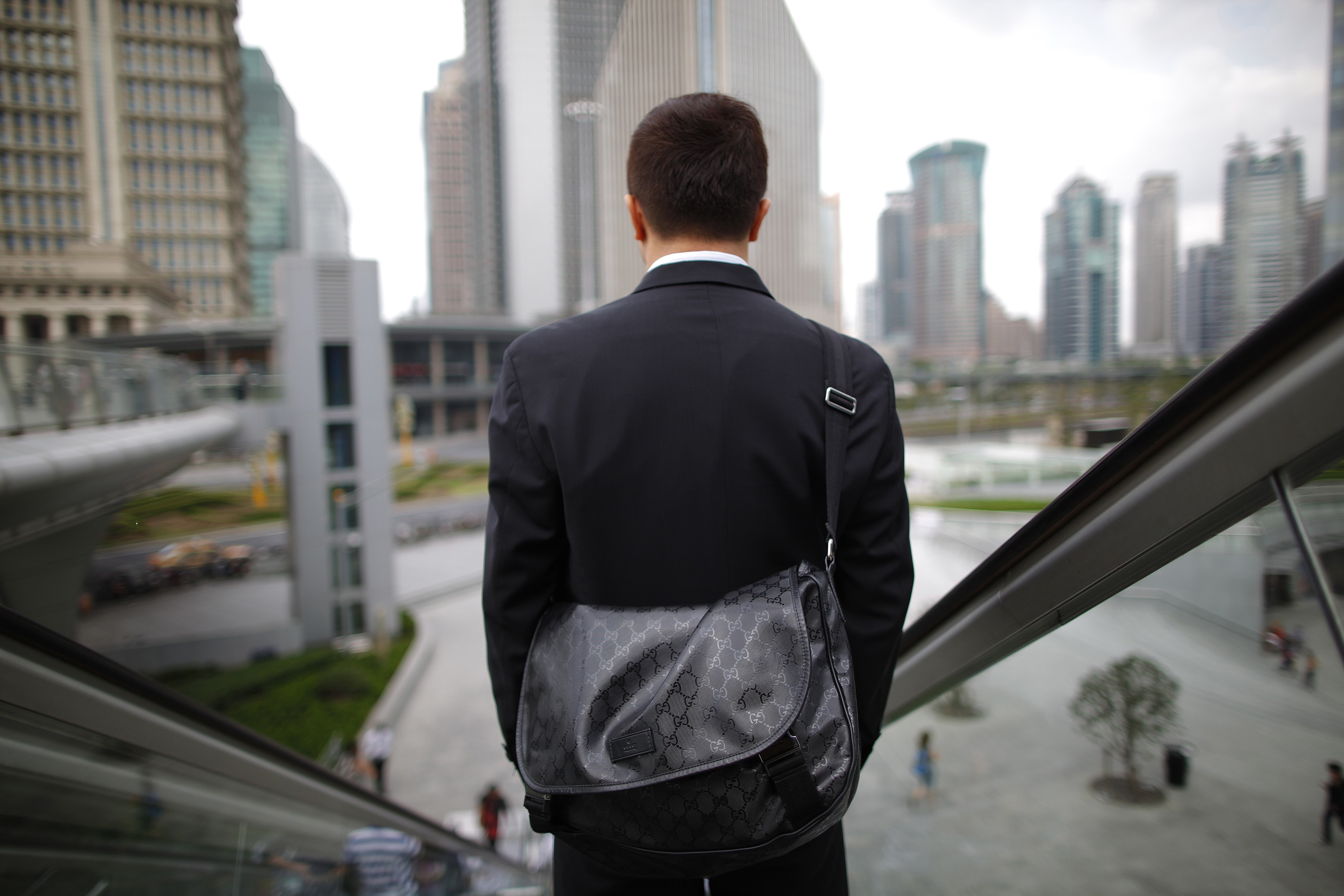 A business man rides an escalator in the financial district of Pudong in Shanghai September 21, 2011. REUTERS/Aly Song (CHINA - Tags: CITYSPACE SOCIETY) - RTR2RVU1      