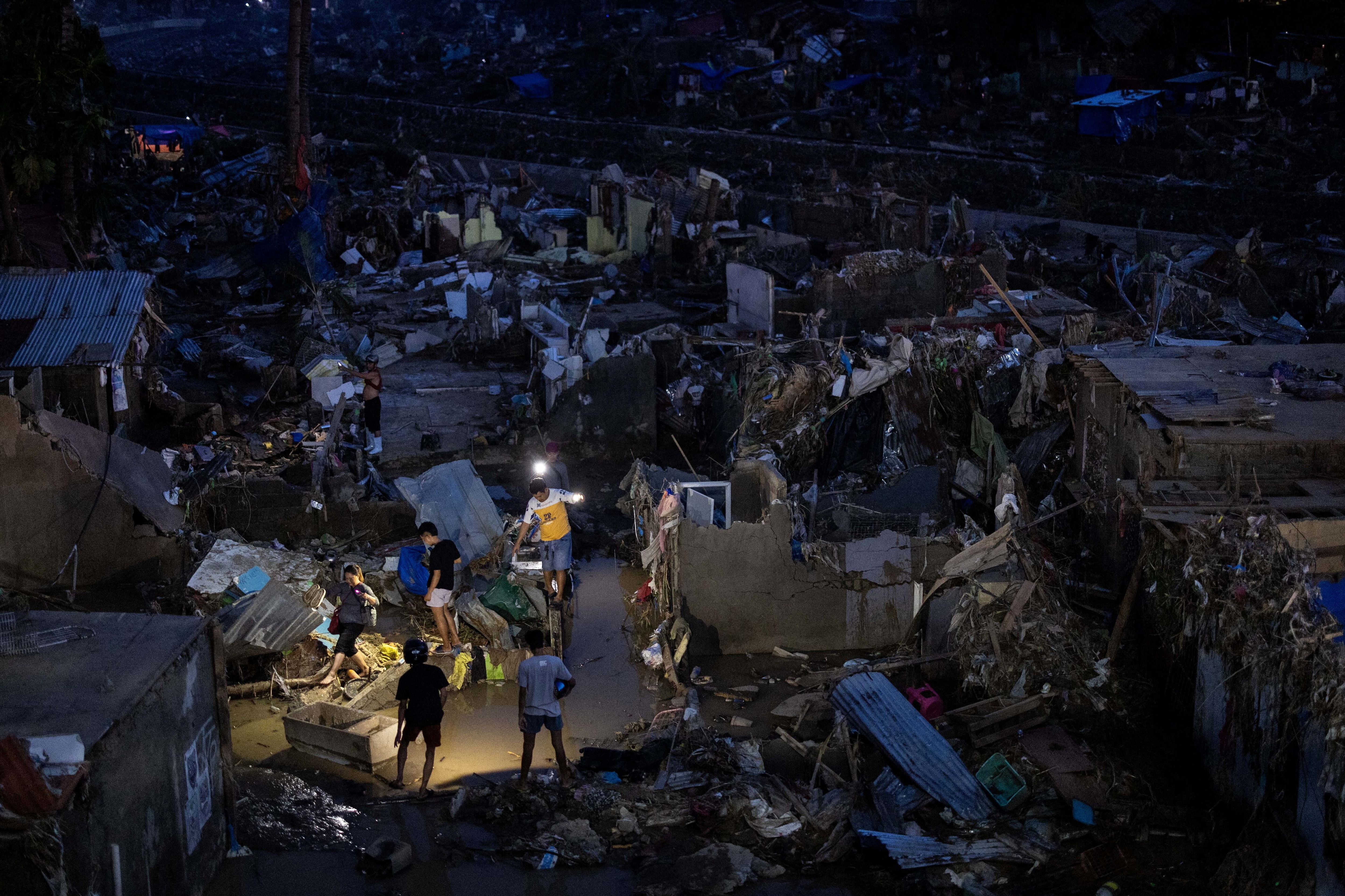 Residents use flashlights to navigate their way out of their community where houses were swept in the floods brought on by Typhoon Kalmaegi in Talisay, Cebu, Philippines, November 6, 2025. REUTERS/Eloisa Lopez